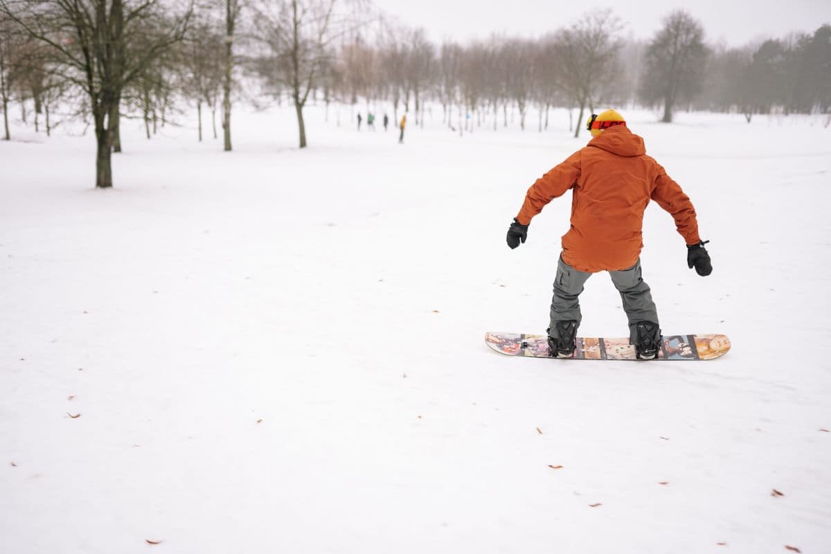 A snowboarder in a winter jacket gliding across a snow-covered field