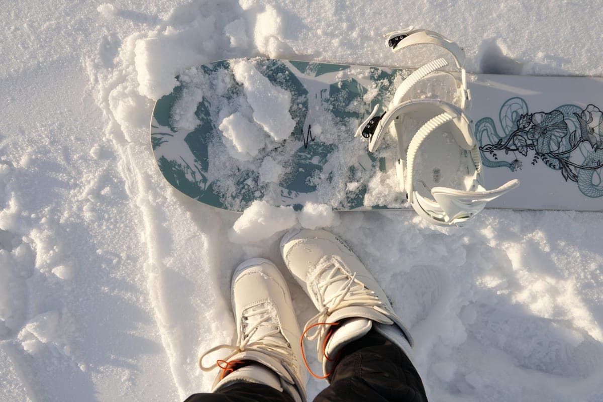 Top-down view of a snowboard and boots resting in fresh snow