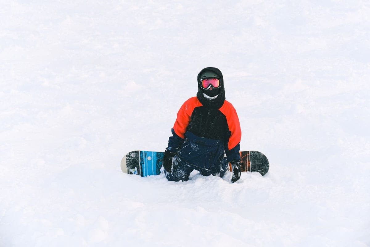 A snowboarder in winter gear resting on fresh snow