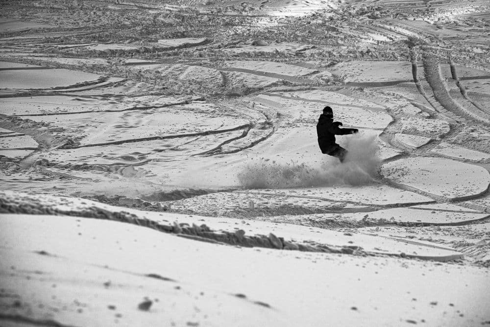 A snowboarder carving through fresh snow on a bright winter day