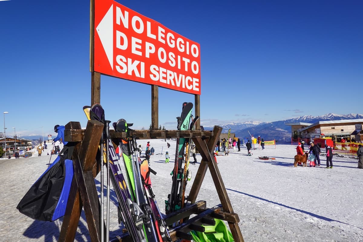 A busy ski service station with racks of equipment and skiers waiting