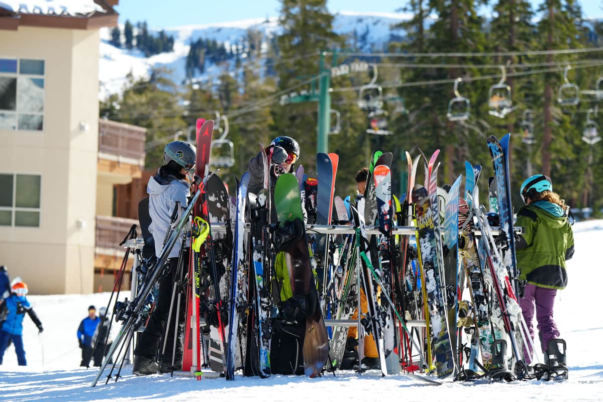 People gathering around skis and boards outside a snowy ski resort