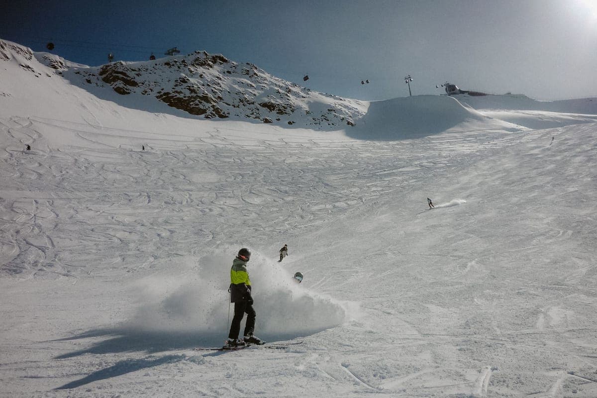 Snowboarder in bright gear carving down a snowy mountain under a clear sky